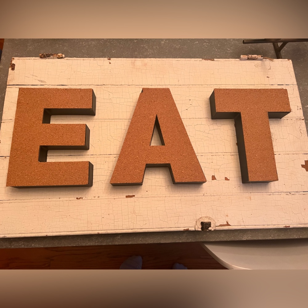 EAT sign on white chippy painted door. Latch and hinges still attached.